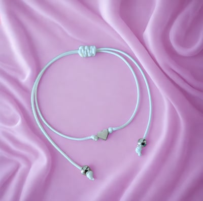 a pair of earphones with a white cord cord and a pink ribbon