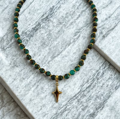 a necklace with a gold starfish charm on a marbled surface