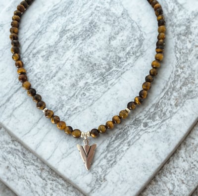 a tiger eye beaded necklace with a silver arrow