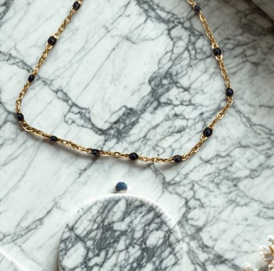 a necklace with a gold chain and a necklace with a black bead