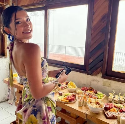 a woman in a dress standing in front of a table with food