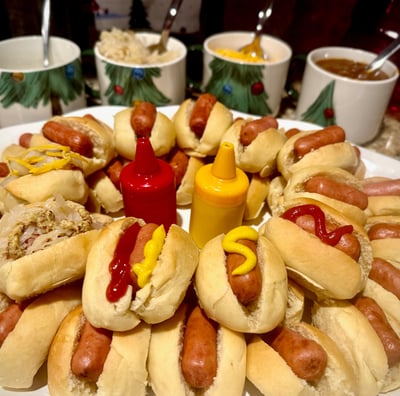 Christmas-themed hotdog bar with Li'l Smokies in Smoky Lil Buns and toppings in Christmas mugs.