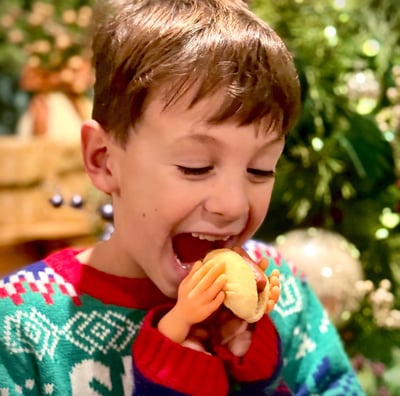 a young boy is eating a Li'l Smoky in a Smoky Little Buns hotdog bun with tiny hands.