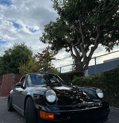 a black porsche 911r parked in front of a fence