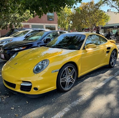 a yellow porsche 9115 parked in a parking lot