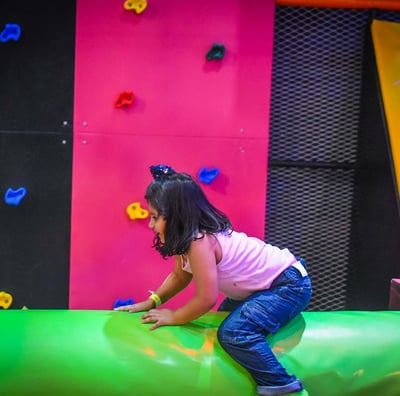 a young girl is playing on a slider in a play area