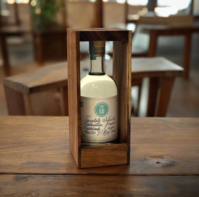 Botella de Lu Mezcal Tepextate Silvestre en una mesa de madera
