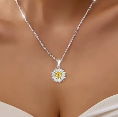 a woman wearing a white dress and a necklace with a yellow flower