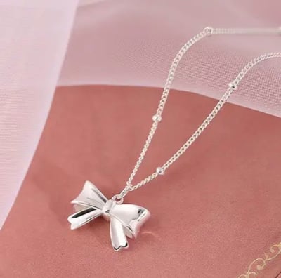 a silver bow tie necklace with a silver bow
