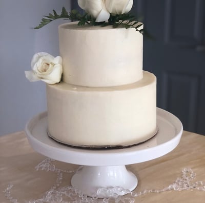 a cake with white frosting and white roses