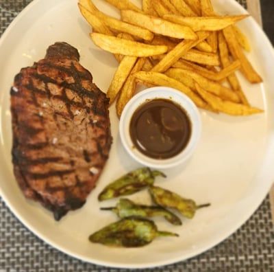 Grilled steak served with French fries and smoky barbecue sauce on a stylish wooden platter