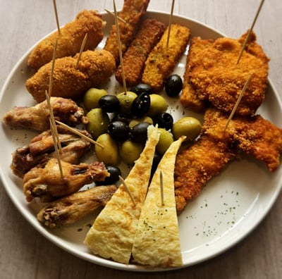 Restaurant table with a complete meal set featuring crispy croquettes, golden fries with aioli, arti