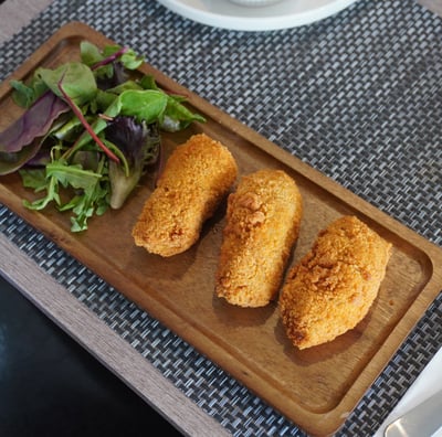 Close-up of crispy chicken croquettes served with mixed green salat.