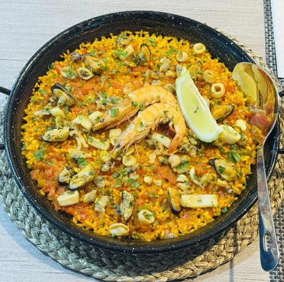 a bowl of Paella food with a spoon and fork