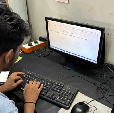 a man sitting at a desk and working with a keyboard and a computer