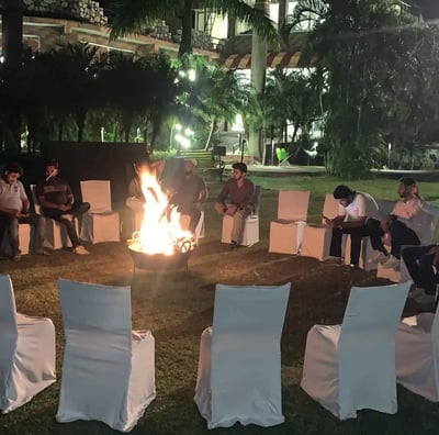 a group of people sitting around a fire pit and having fun