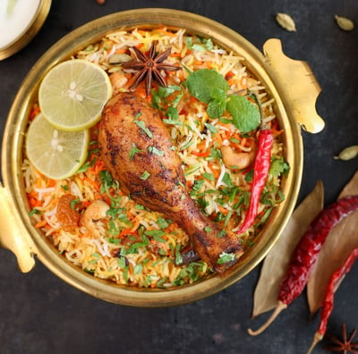 a chicken dum biryani rice dish with a chicken and vegetables