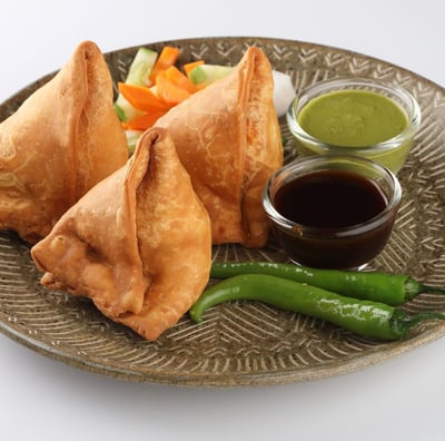 A plate of samosa platter with tamarind and mint chutney