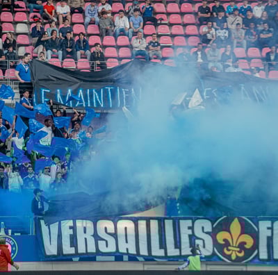 Groupe de supporters de Versailles qui craquent des fumigènes