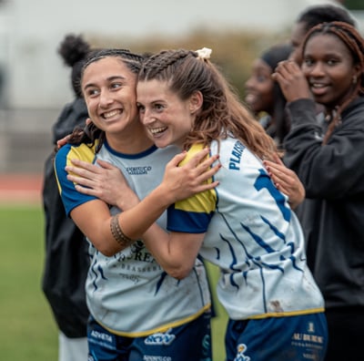 Deux joueuses qui font une accolade en souriant après la victoire