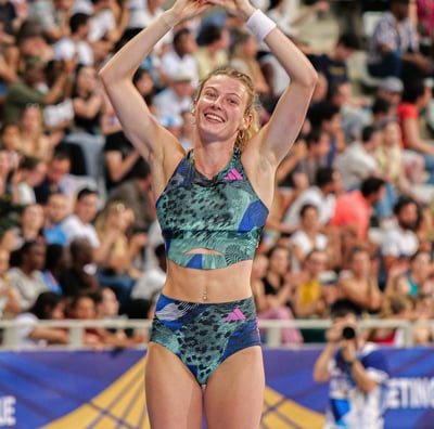Margot Chevrier fait un cœur avec ses mais sur le tapis de saut après avoir sauté