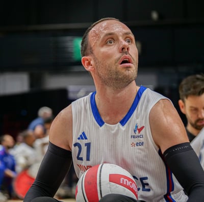 Joueur de rugby fauteuil de l'équipe de France avec le ballon qui regarde au loin