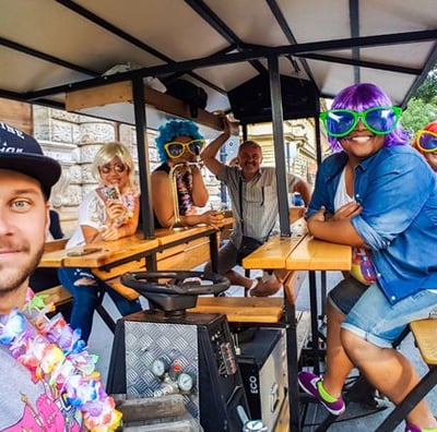 a man and woman sitting at a table of Riga Beer Bike with a man in a colorful costume