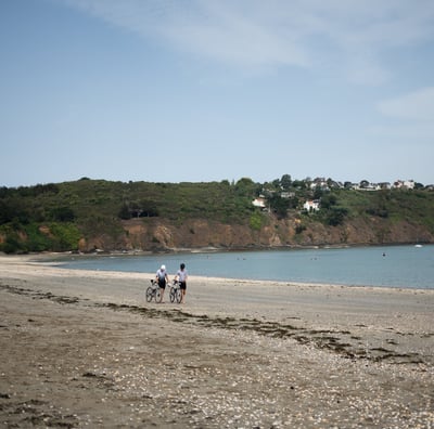 a couple of people riding bikes on a beach