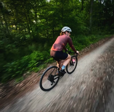 a woman riding a bike on a dirt road