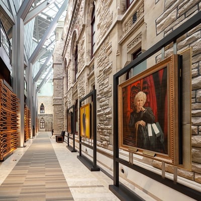 a hallway with a glass roof decorated with portrait art displays