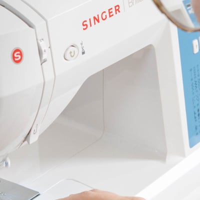 Vu de dos d'une personne cousant sur une machine à coudre