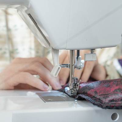Gros plan sur des mains guidant le tissus sur une machine à coudre