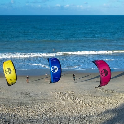 3 kites voando em frente a praia.