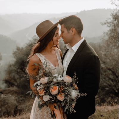 a young modern couple posing for there wedding pictures, the bride is wearing a hat