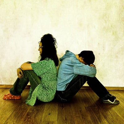 a man and woman sitting back to back on the floor