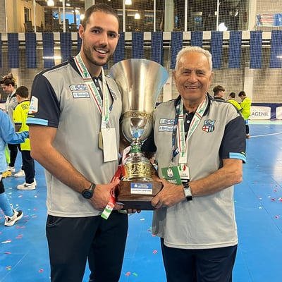 two men standing next to each other holding a trophy