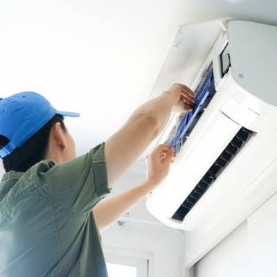 a man in a blue hat is fixing a air conditioner