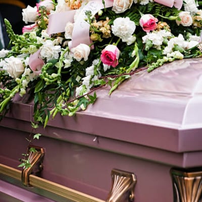 a off pink coffin with a casket sprays of cornations and roses