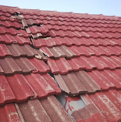 Cracked and missing roof tiles exposing underlay