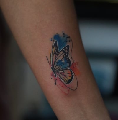 Butterfly tattoo with music notes watercolor fill on arm by Dudo’s Hyderabad
