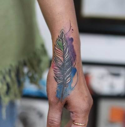 Blue and purple watercolor feather tattoo at Dudo’s Tattoos Hyderabad