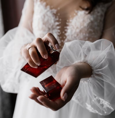 a woman in a white dress holding a red perfume bottle