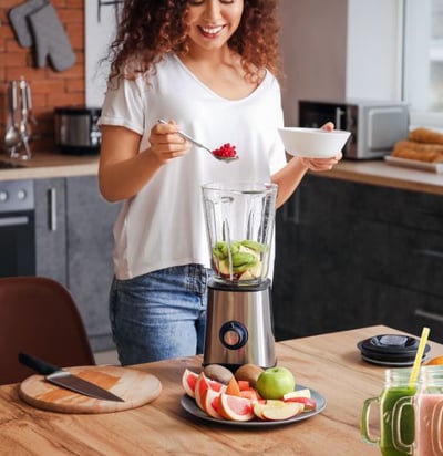 a woman is standing in front of a blender