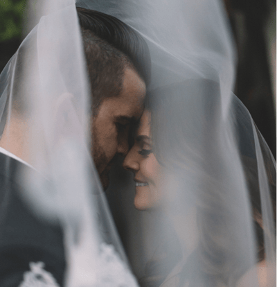a bride and groom are standing in front of a veil