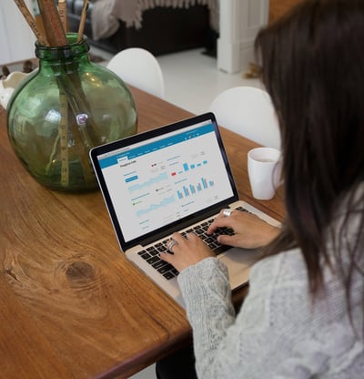 a woman sitting at a table with a laptop computer displaying Xero software