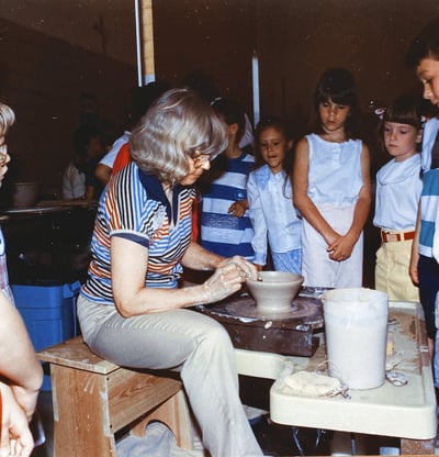 Naoma Powell throwing on the wheel in front of a class of elementary students.