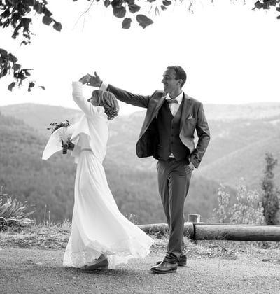 Photo en noir et blanc de mariés qui dansent devant la mairie lors de leur journée de mariage