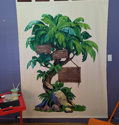 Linen canvas tapestry mural of a lush tree in greens and blues with hanging signs on three branches. Work in Progress.