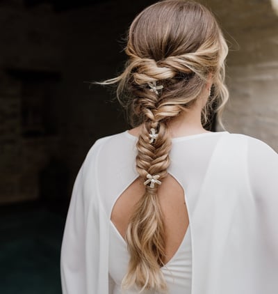 Blonde bride wearing her hair in a fishtail braid and pearl hair accessories
