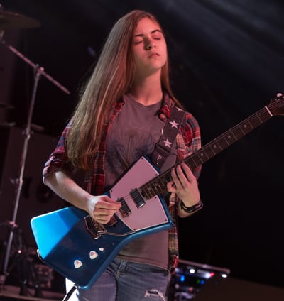 Gurnee Guitar Academy Guitar Lessons a girl playing guitar in a concert